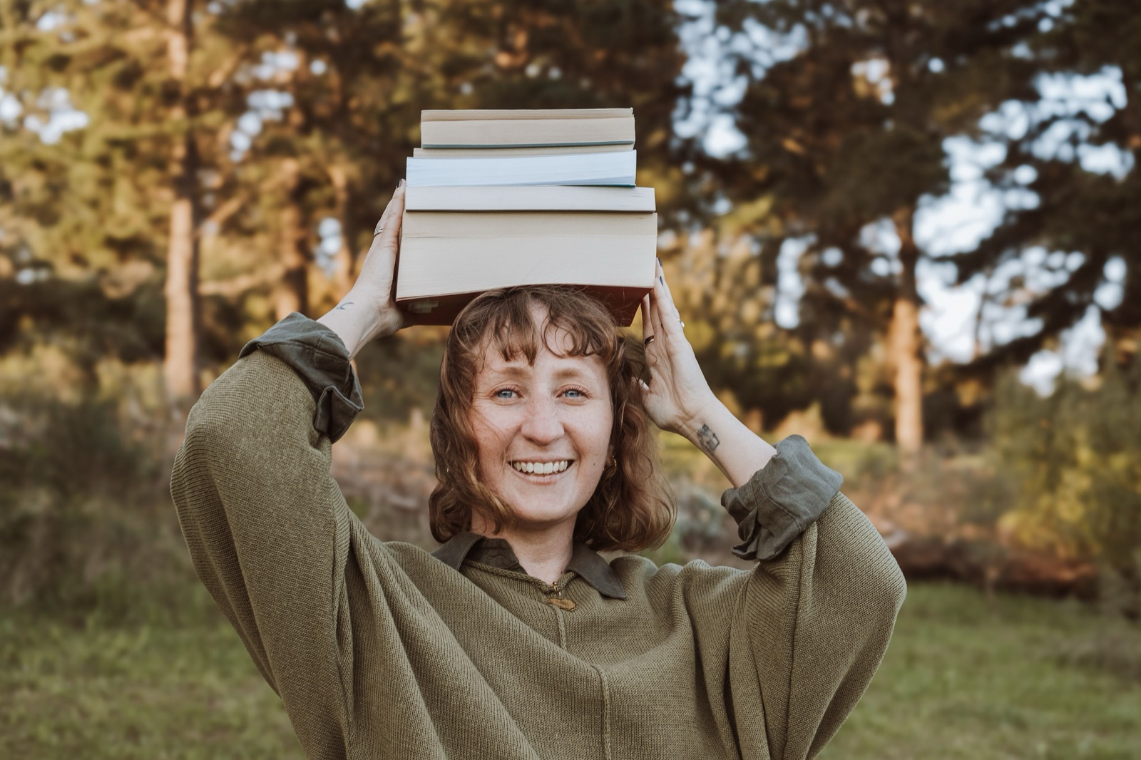 Bronwen smiling with a stack of books balanced on her head