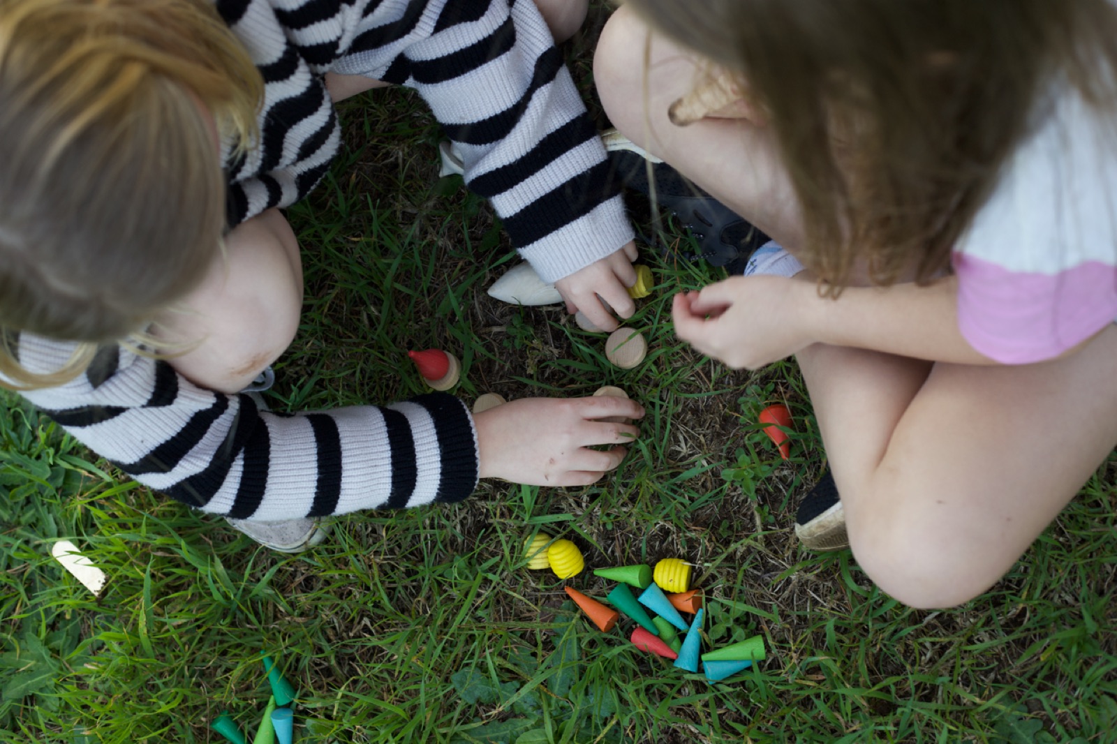 Two children playing with small toys on the grass
